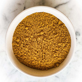 Curry powder in a white bowl on a white marble background