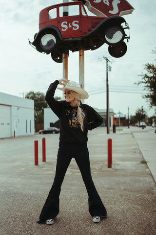 Woman modeling the Pendleton rodeo hoodie in black color.  The hoodie features a rodeo scene with cowboy riding a bronc.