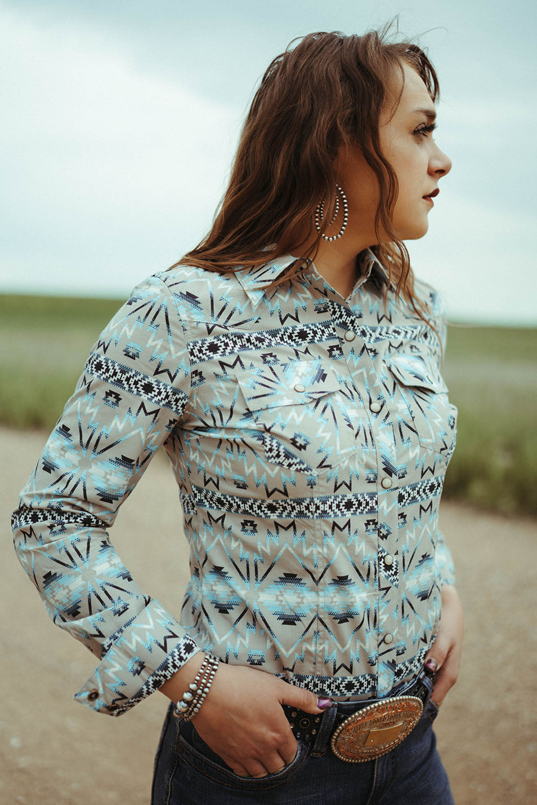 Woman standing on dirt road modeling the Aztec Print Snap Shirt.  