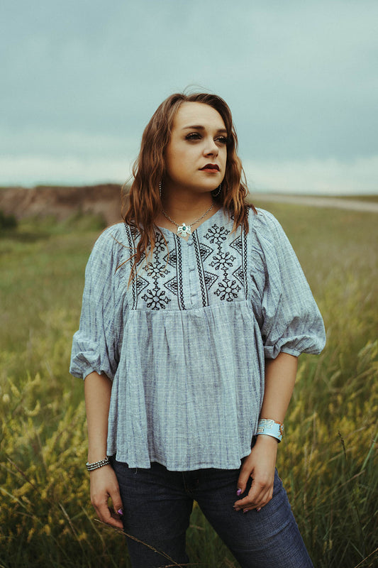 Woman standing in field modeling the Blue Button Up Embroidered Shirt.  