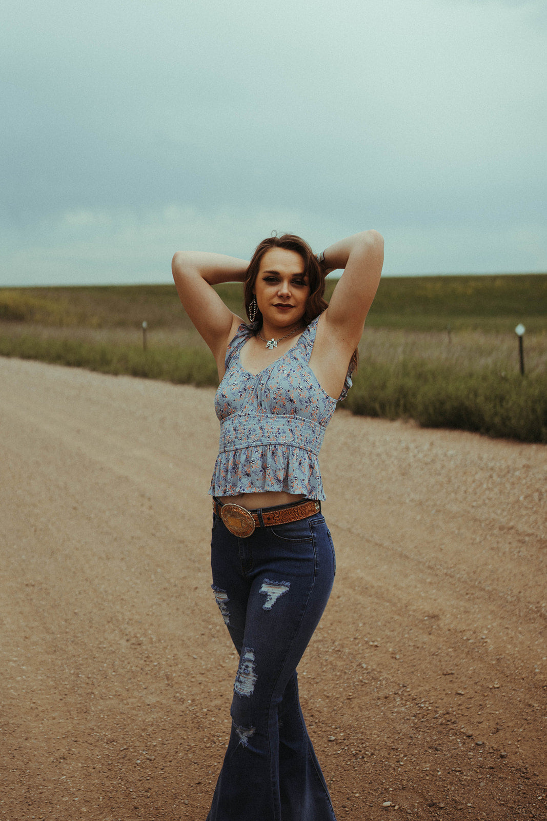 Womnan standing on dirt road wearing the Floral Flutter Top by Rock & Roll Denim.   Tank style. 