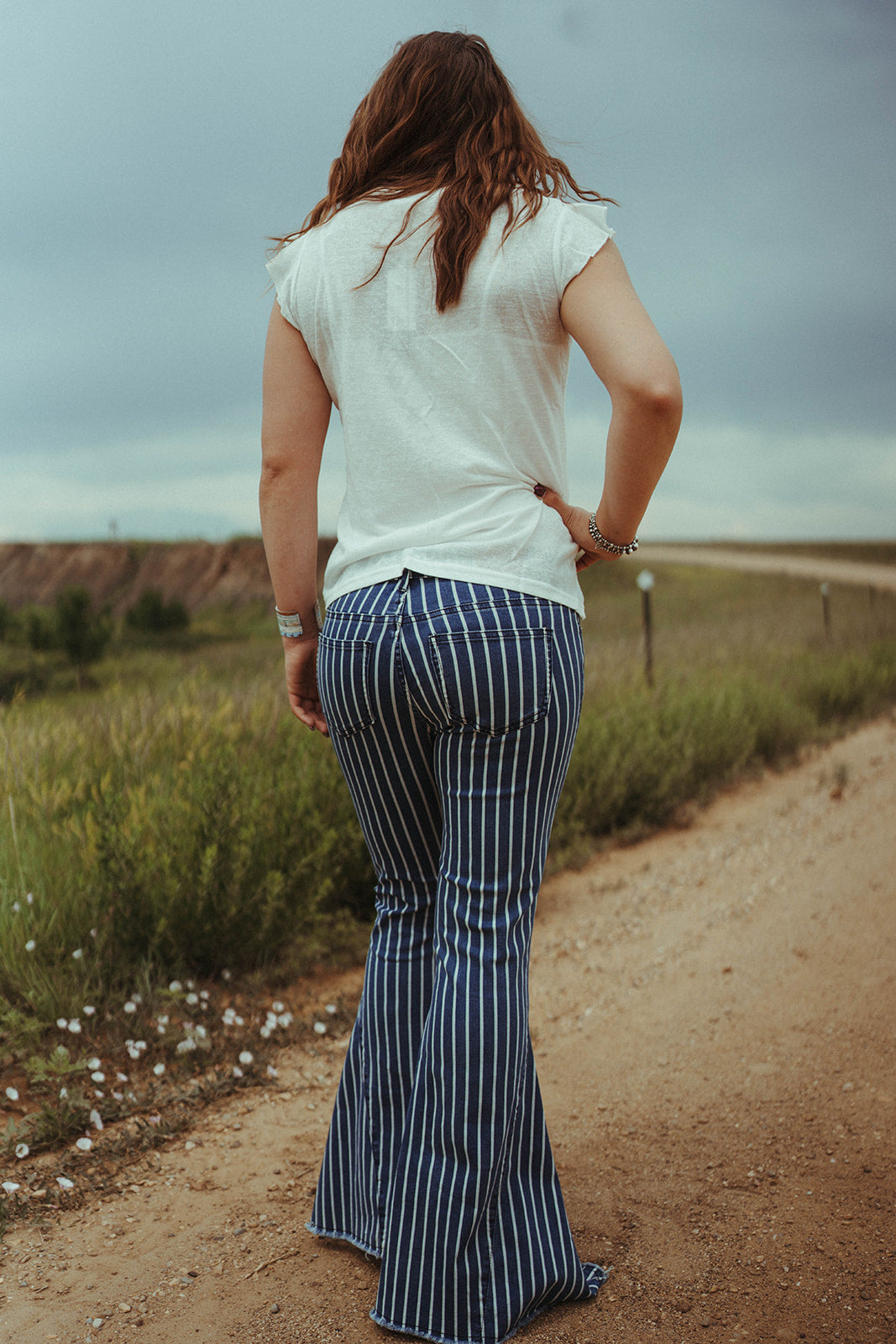 Woman modeling the back of the Home Folk Stripe Flares.  2 front and back pockets.  Belt loops, Zip Fly. 