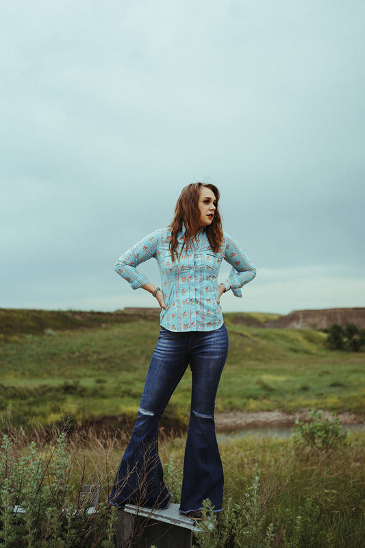 WOman standing in field modeling the Dark Wash Distressed Knee Flares.  