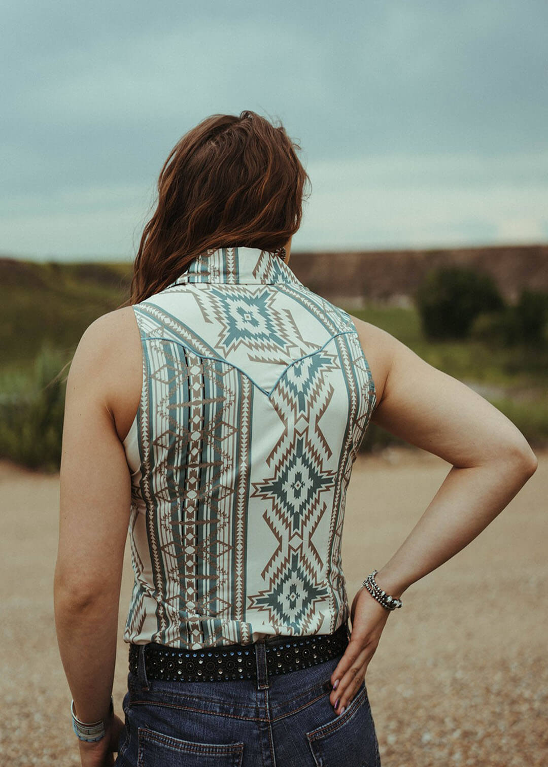 Woman modeilng the back of the Aztec Sleeveless Snap shirt.  The shirt is collared.  