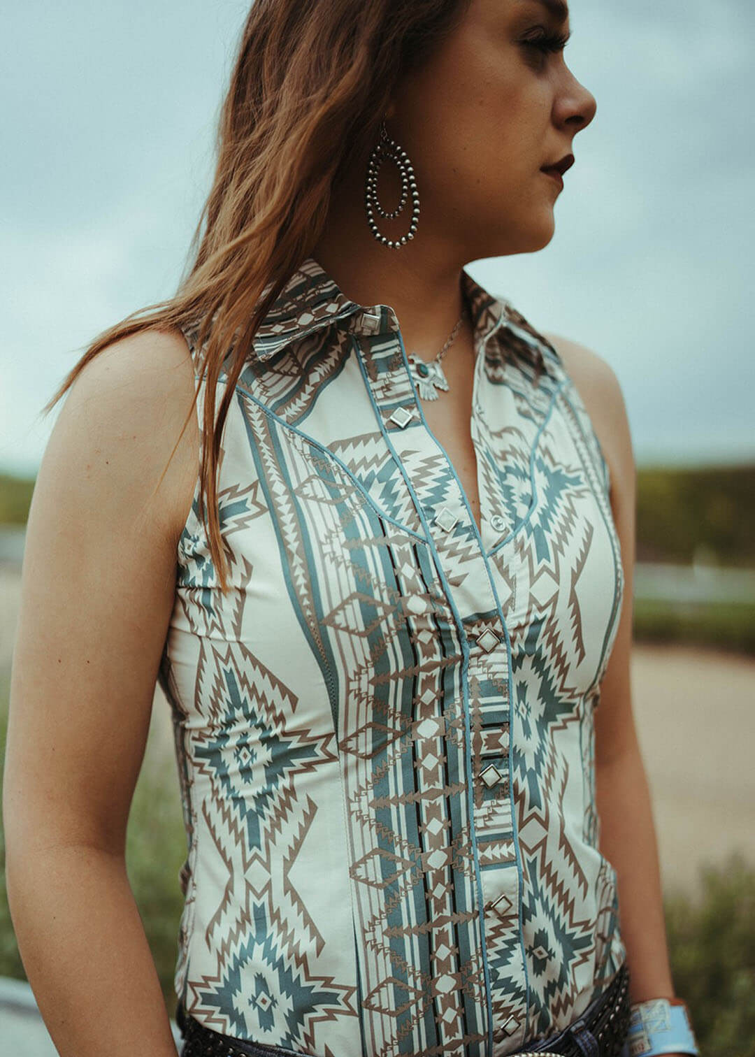 Close up image of the Aztec Sleeveless Snap shirt.  Has colors of teal, white, and tan.