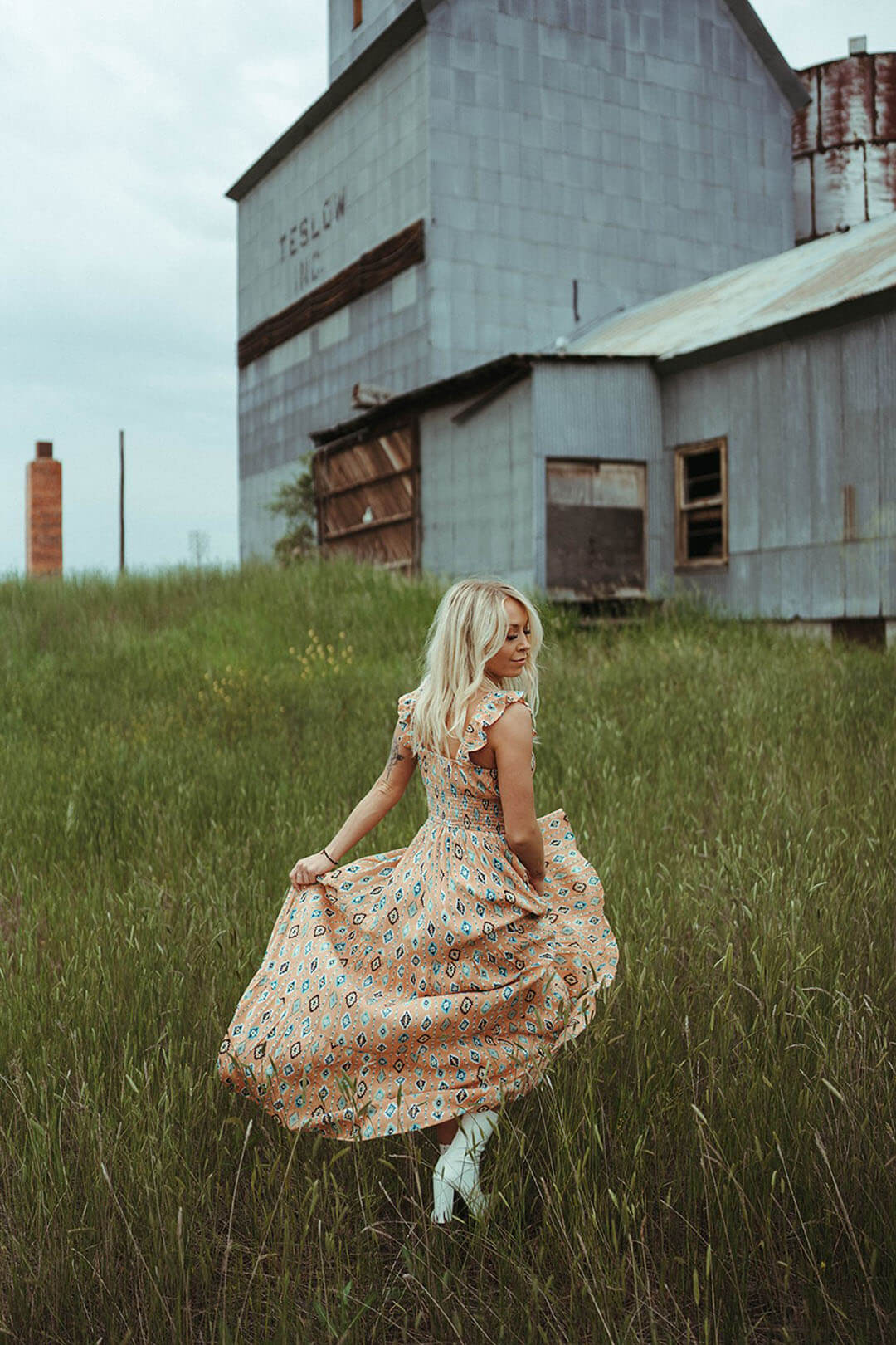 Woman wearing the Aztec Tiered Maxi Dress in field showing the back of the dress. Beautiful flowy dress. 