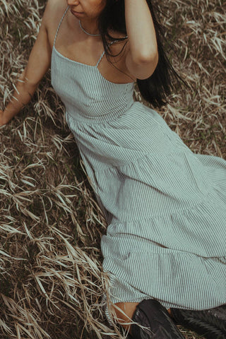 Woman laying down in field wearing the Black & White Striped Dress.  