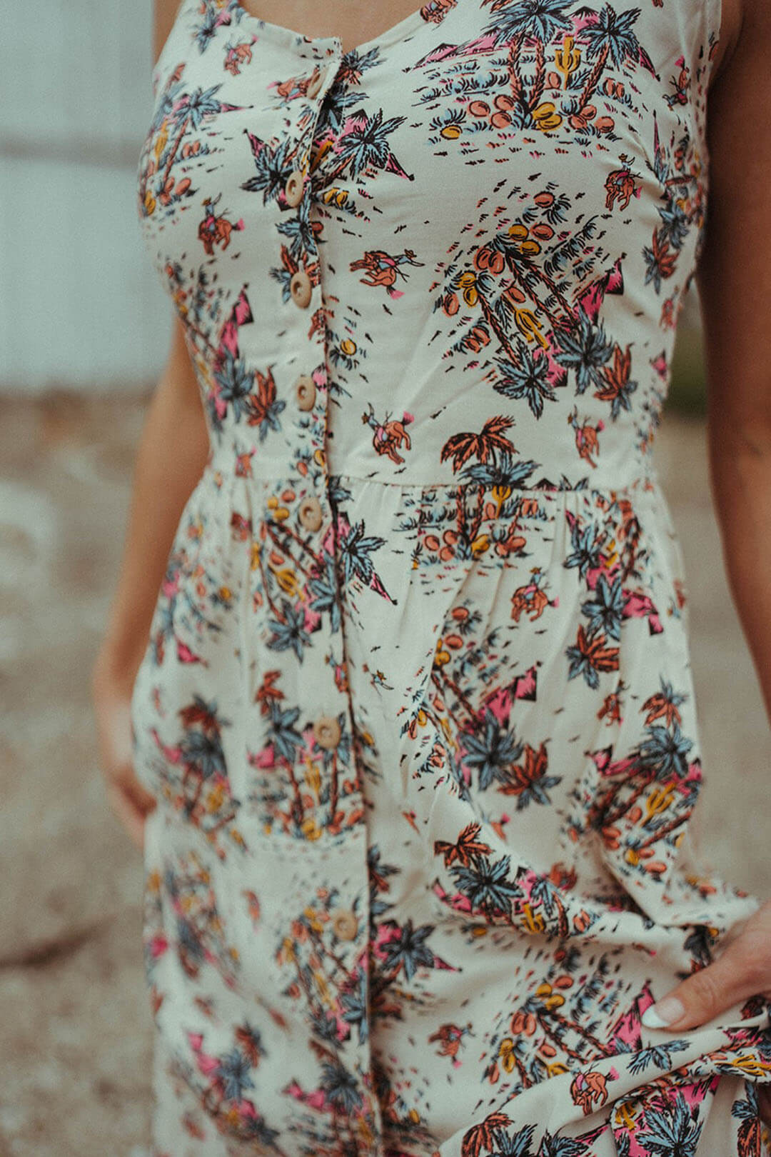 Close up image of the Summer Button Down Dress featuring Palm Tress and Western Scene.  White in color dress with multiple colors throughout. 