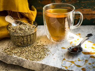 A brewed mug of Yerba Mate Tea sits next to a glass jar filled with the dried tea.