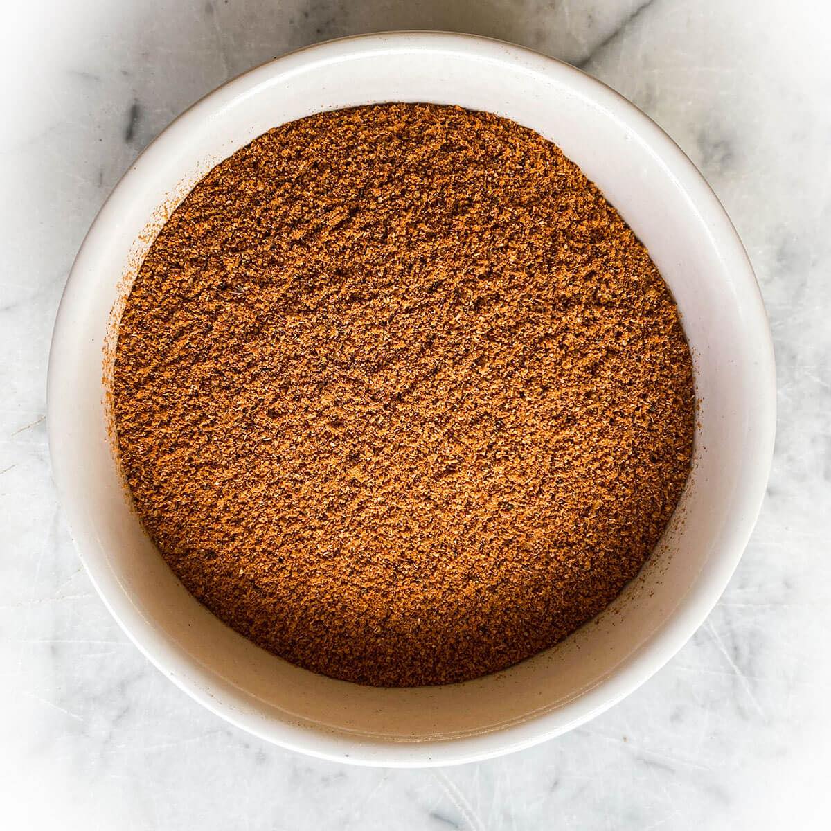 Cajun spice blend in white bowl on marble background