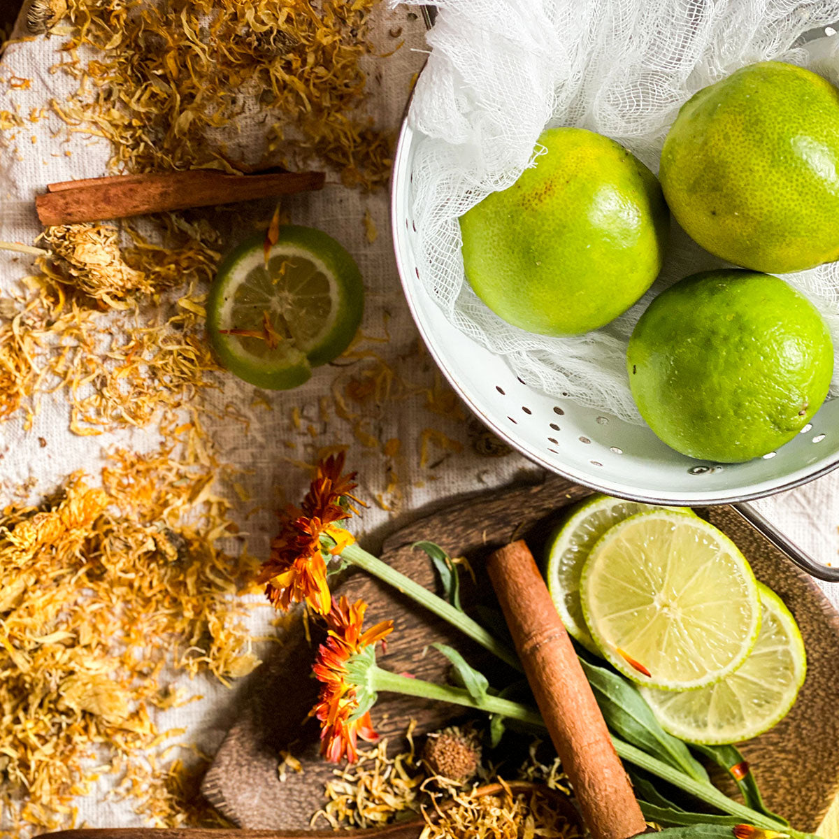Dried calendula flowers on a table with a bowl of limes