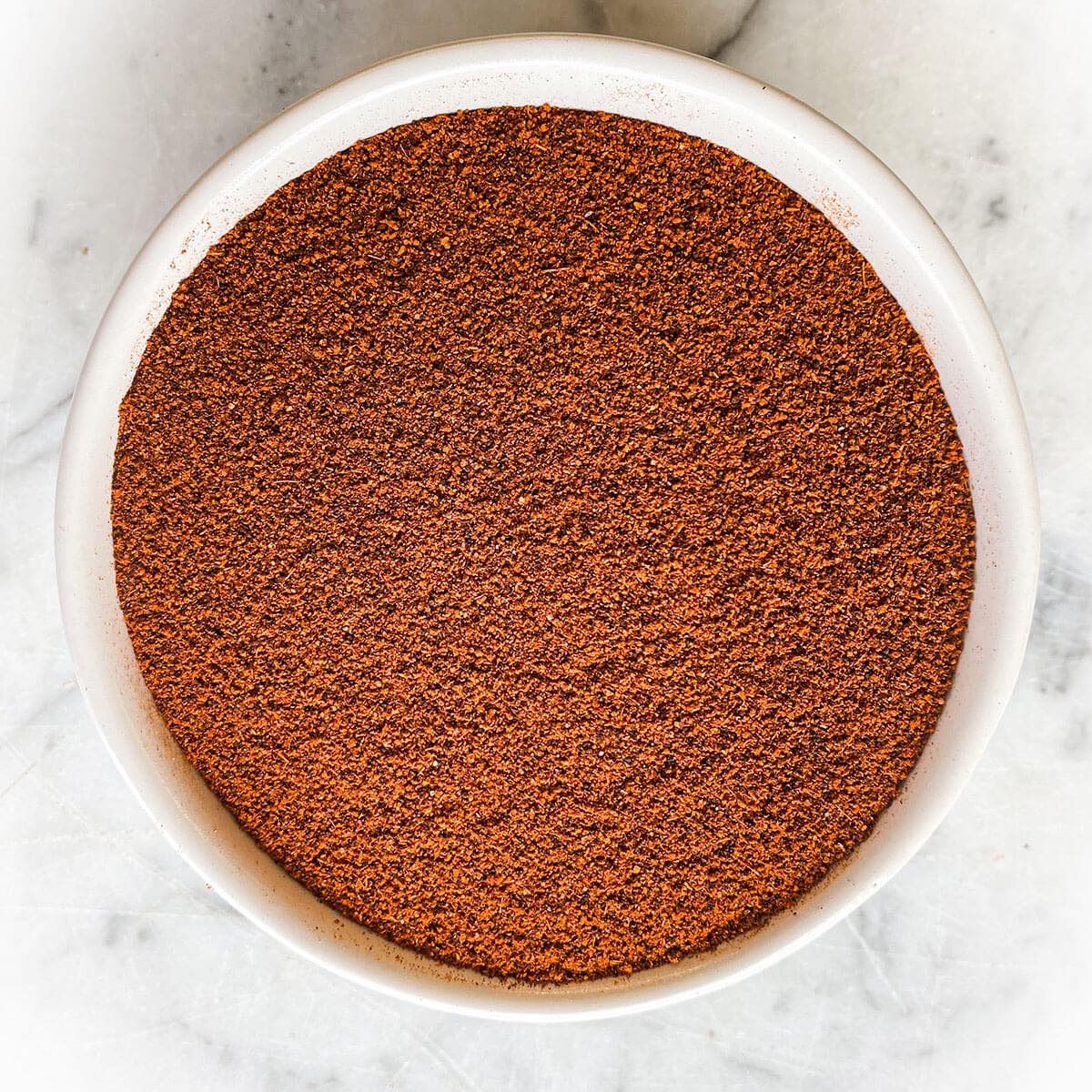 Chili powder blend in a white bowl with a white marble background