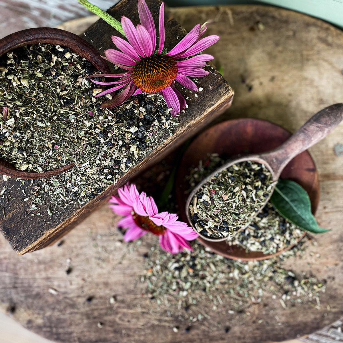 Double E tea in a bowl overflowing onto the table surface with a wooden spoon in the foreground filled with the dried tea