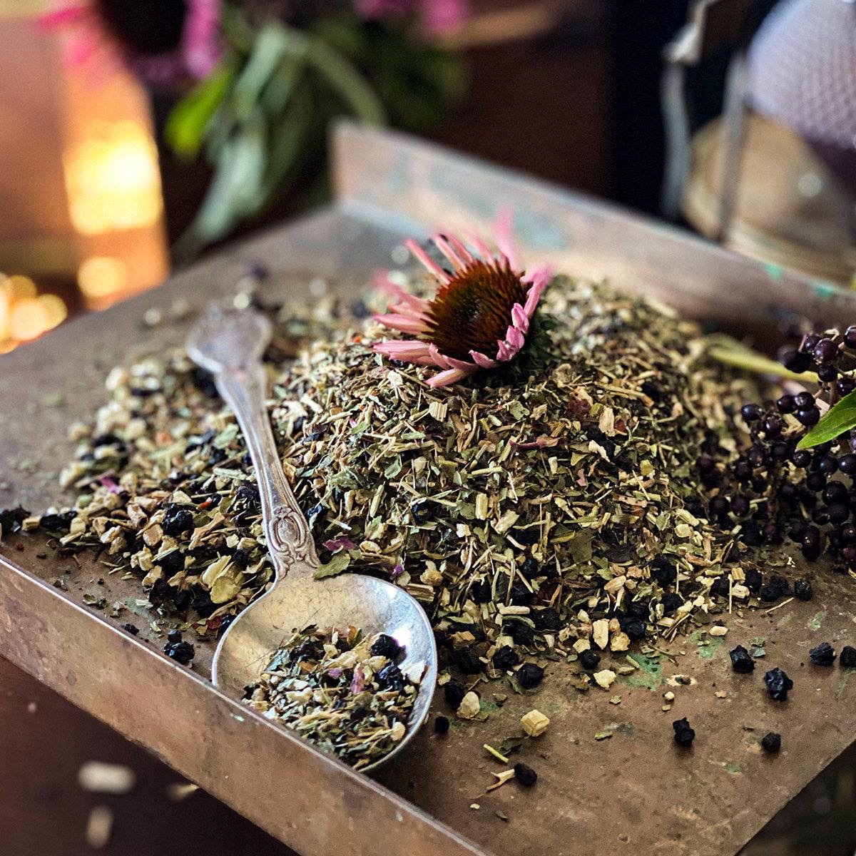 Dried Double E Tea on a metal scale with a spoon of the tea spilling out 