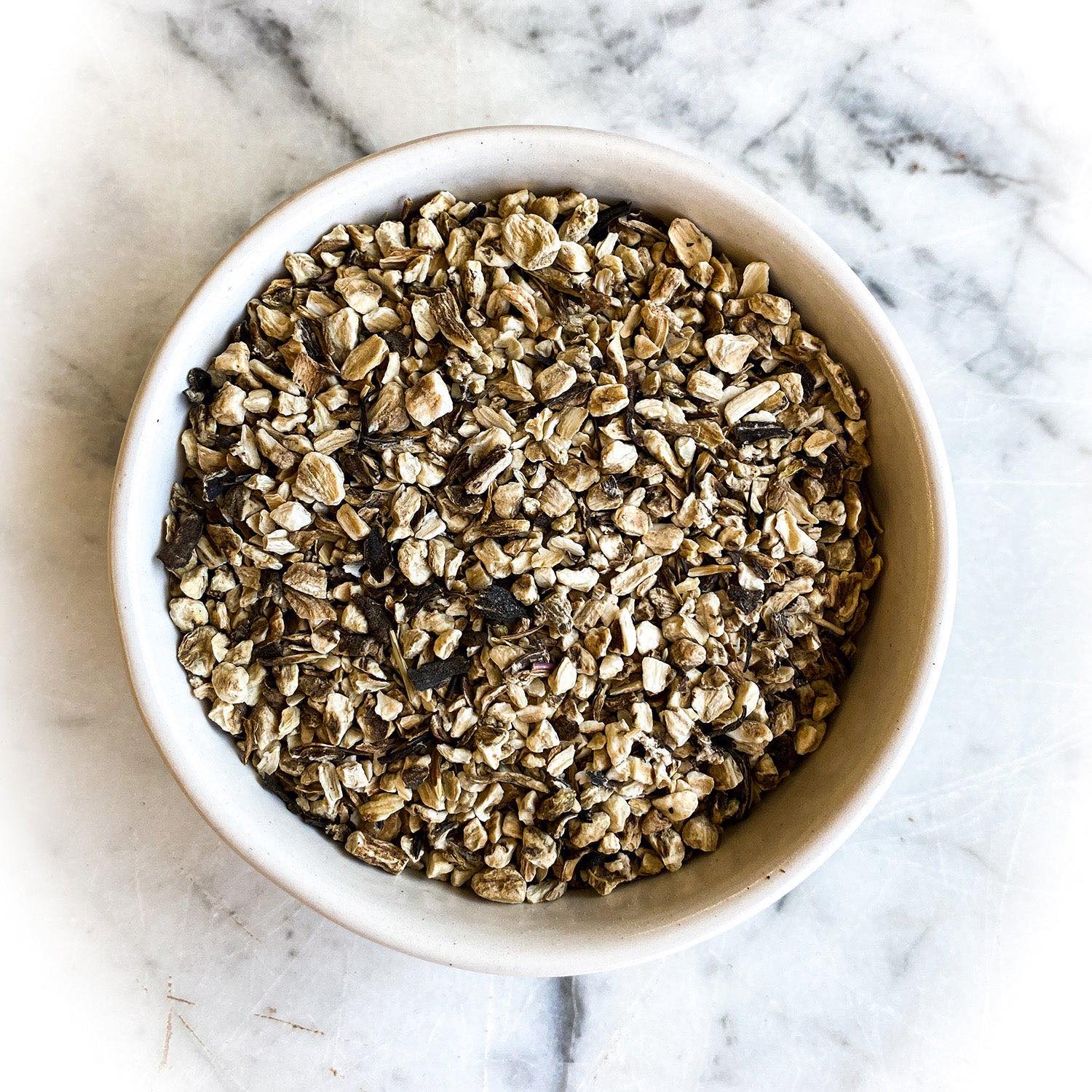 White bowl filled with burdock root on a marble countertop.