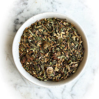 A bowl filled with dried Cough Tea sits on a white marble surface.