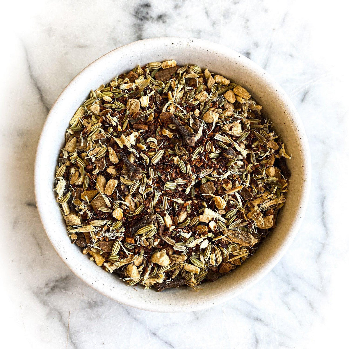 Dried Gingersnap Tea in a white bowl on a white marble background.