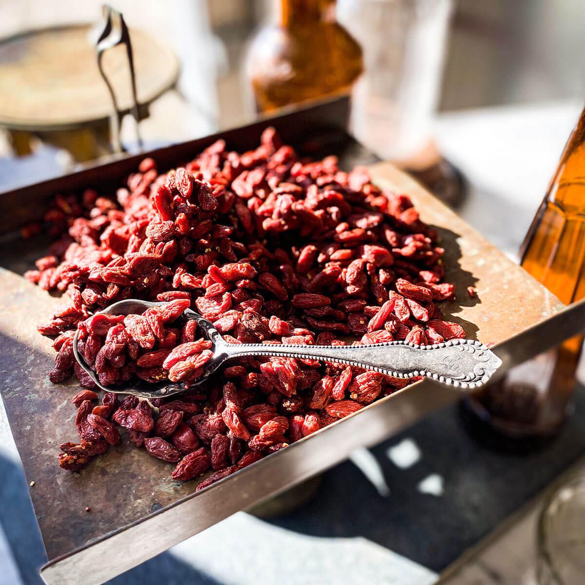 Dried goji berries on a metal scale with a spoon filled with dried gojis
