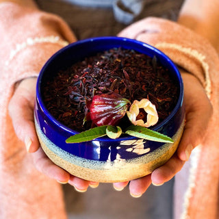Dried hibiscus flowers in a bowl held in a woman's hands