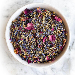 Herbal bath mix in a white bowl on a white marble background