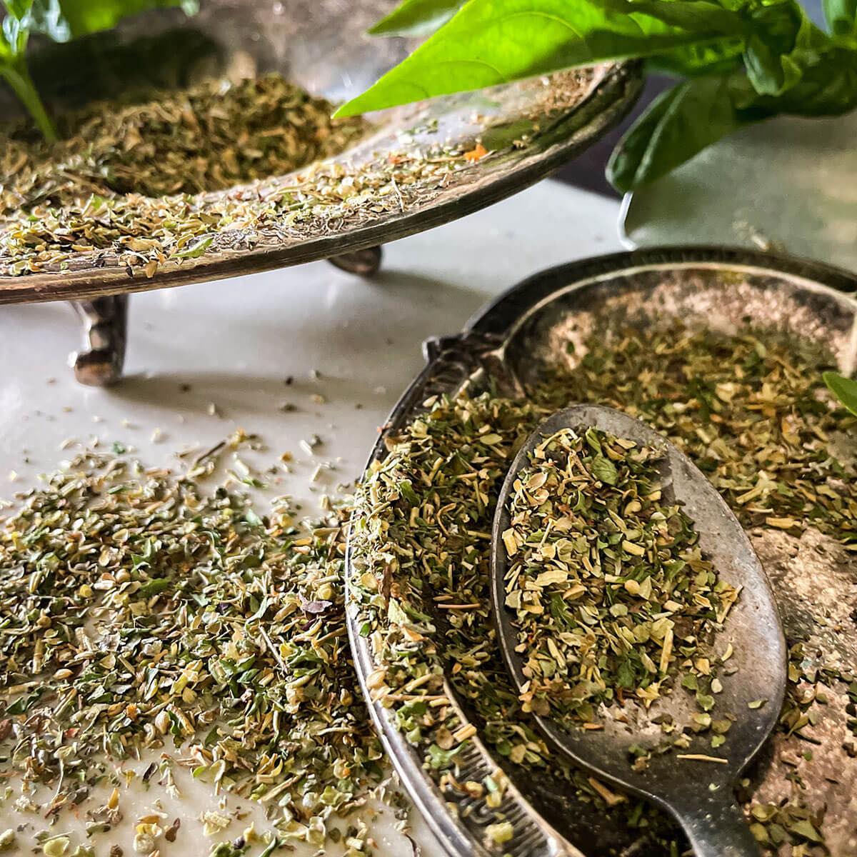 Italian seasonong blend spills from a silver spoon into a dish
