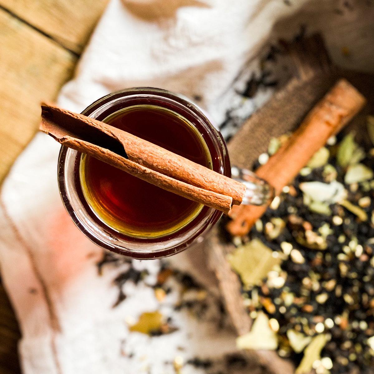 Overhead shot of brewed black spice chai tea with a cinnamon stick on top of the mug.