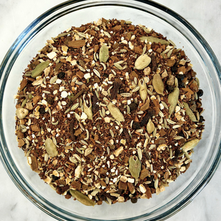 Unbrewed Red Rooibos Spice Chai Tea in a clear glass bowl on a marble background.