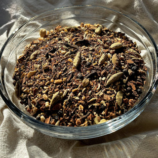 Unbrewed Red Rooibos Spice Chai Tea in a clear glass bowl on a cream fabric background.
