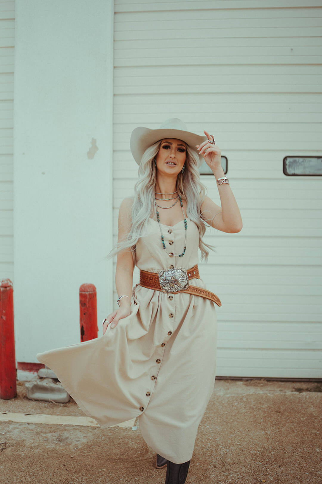 Woman modeling the Button Down Midi dress in a natural tan color.  The dress has spaghetti straps.