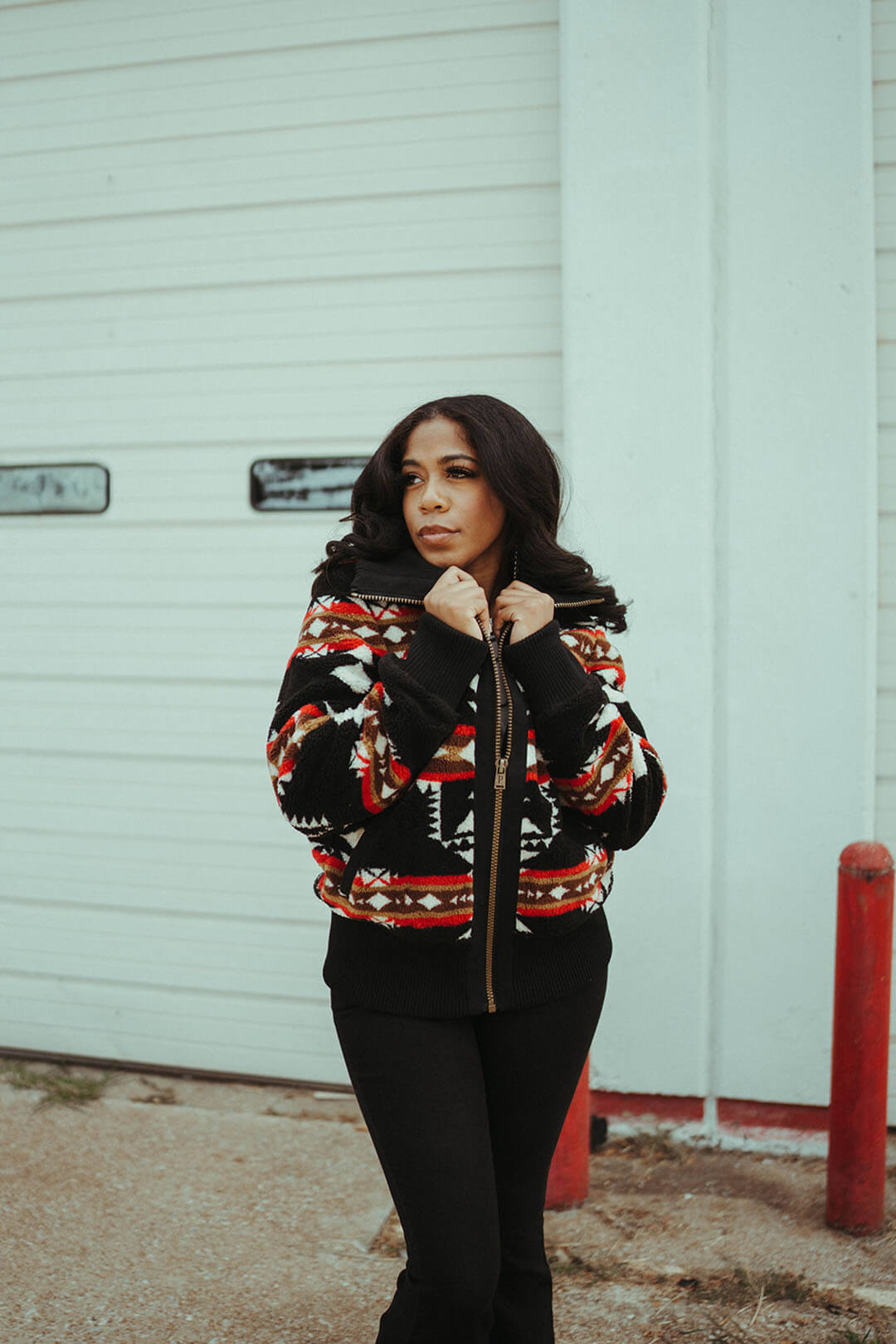 Woman modeling the foxglove range fleece bomber by pendleton.  The bomber/jacket is black and features an aztec pattern throughout in red cream and white colors.