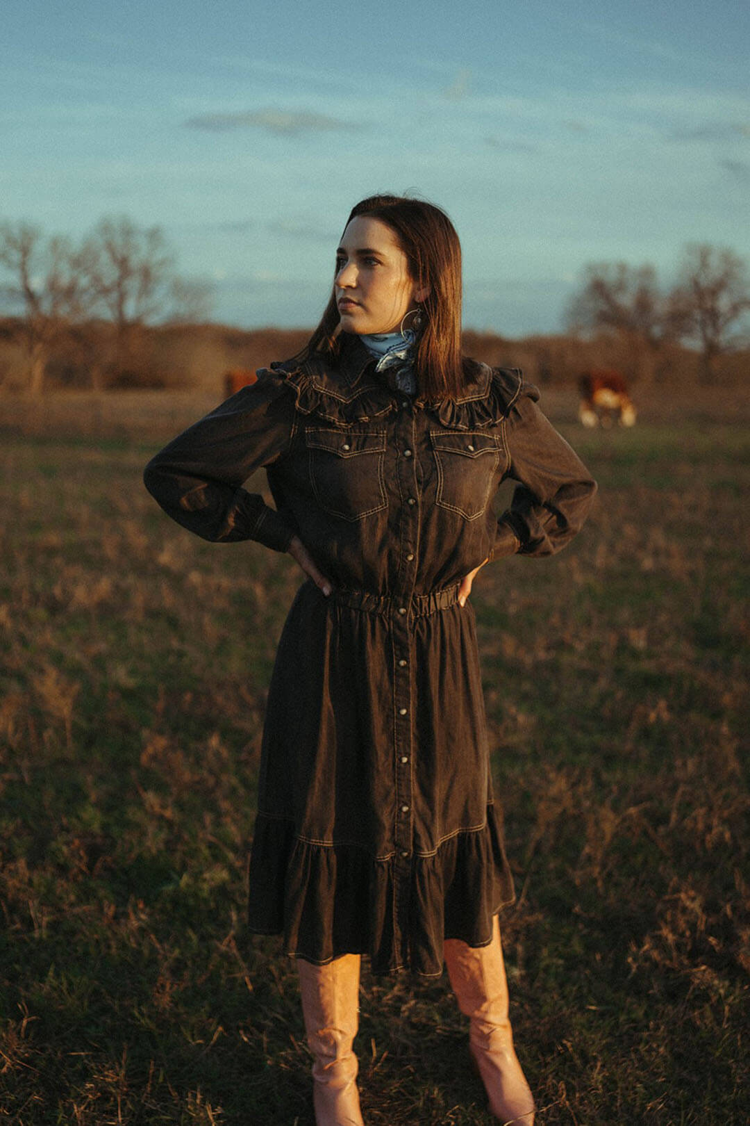 Woman standing in field wearing the Ace High Dress.  The dress is a perfect piece transitioning out of winter to spring.  The Dress has snap buttons all the way down the front.  