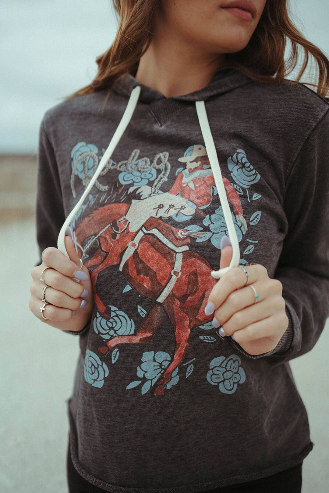 Close up picture of the Bronc Rider Rose Graphic XOXO brand hoodie.  The shirt can be worn in every season. 