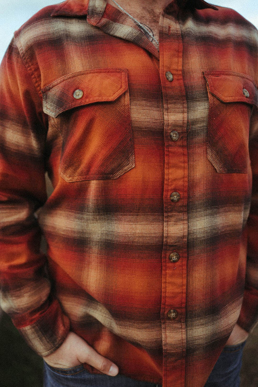 Close up image of the Burnside Flannel BUtton up Shirt.  The color is a burn orange color with hues of creams/browns. Featuring chest pockets on each side that button. 