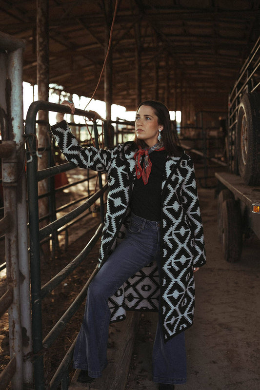 Girl modeling the Cripple Creek Southwestern Hooded Duster.  The duster is black and white aztec print.  