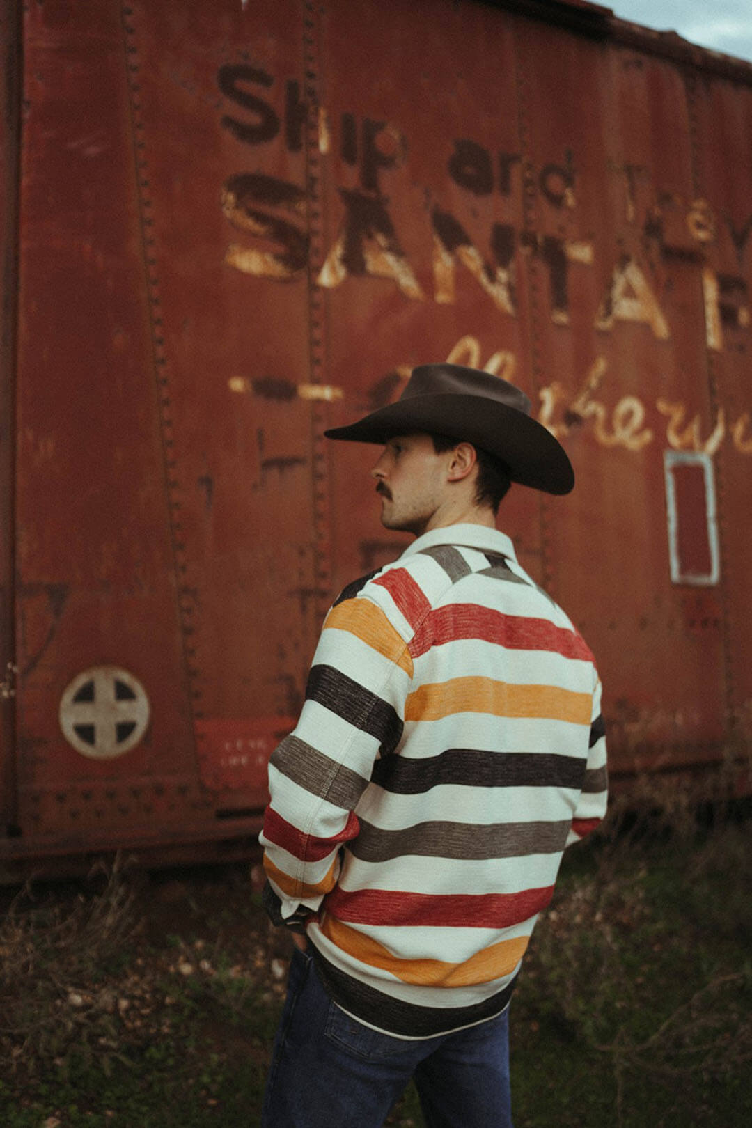 Man modeling the back side of the Driftwood pendleton shirt in colorful stripes.  Features a collar.