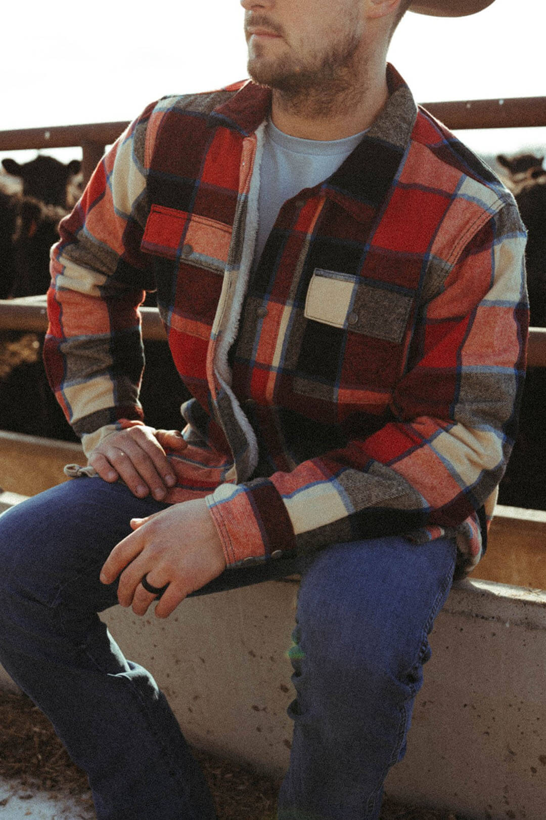 Man sitting down wearing the Flannel Sherpa Jacket by Wrangler.  The jacket features 2 front snap closure pockets.