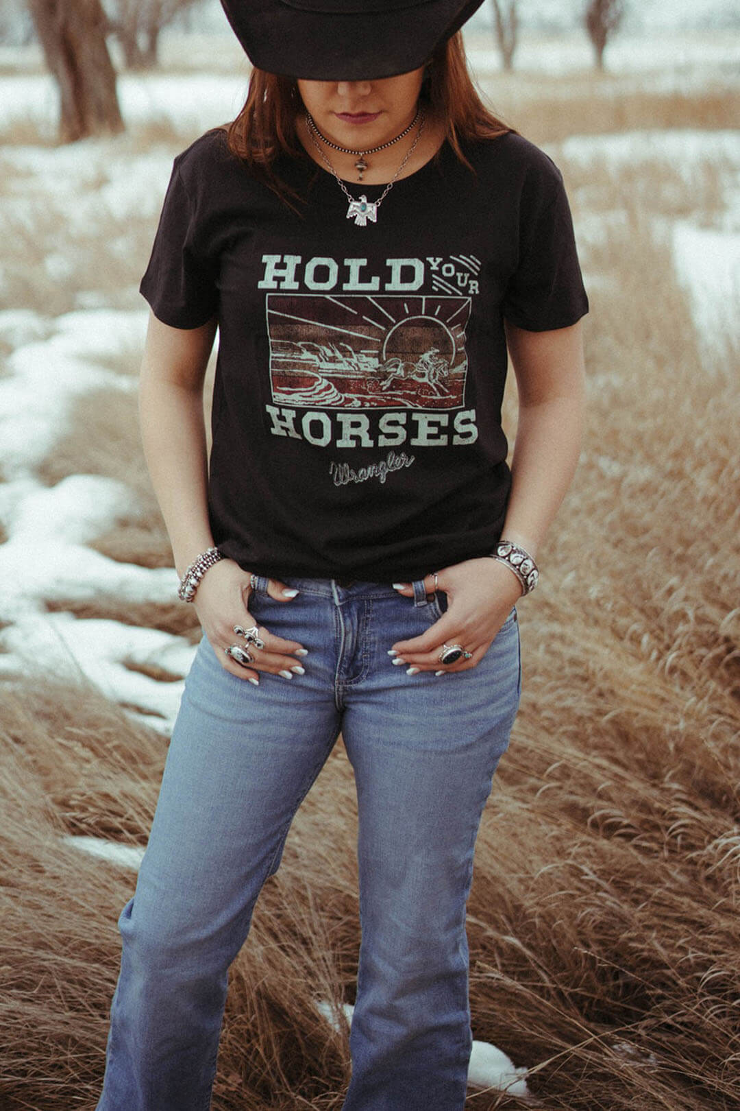 Woman modeling the wrangler graphic tee with the words "Hold Your Horses"  