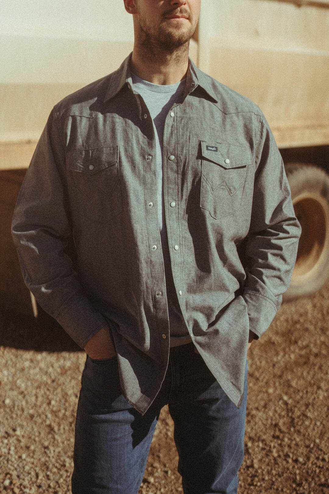 Man modeling the Gray Wrangler Pearl Snap Shirt featuring 2 front chest pearl snap pockets.