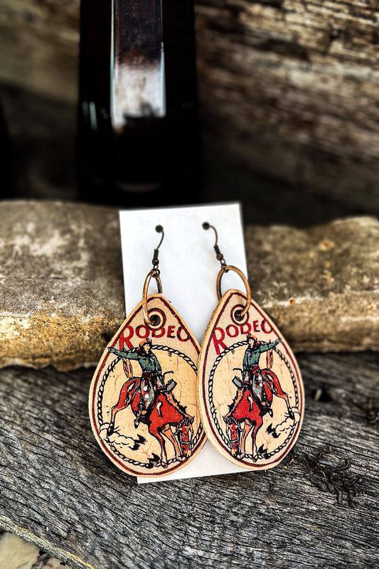 Picture of the XOXO art & company earrings.  The scene is of a cowboy riding a bronc with the saying "Rodeo"