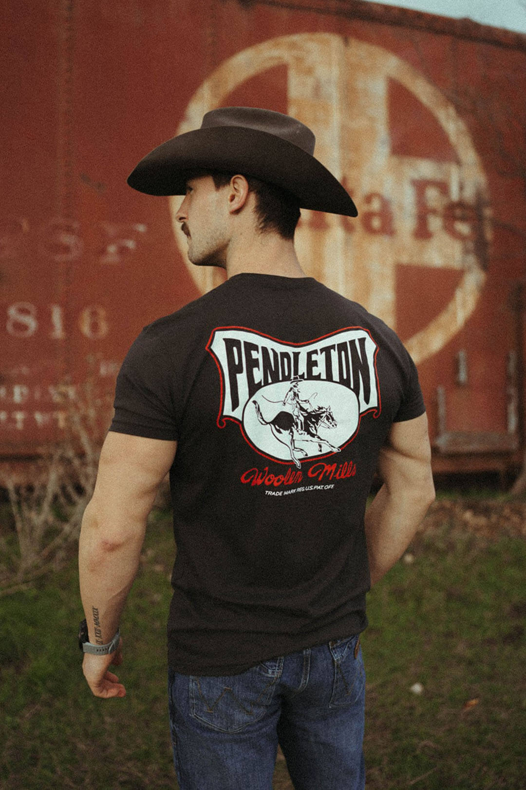 Man modeling the back side of the pendleton rodeo rider graphic tee featuring a picture of a cowboy on horse with the words "Pendleton" across back.  