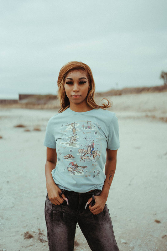 Woman modeling the Ranch graphic tee by XOXO art & company.  The shirt features western scenes. 