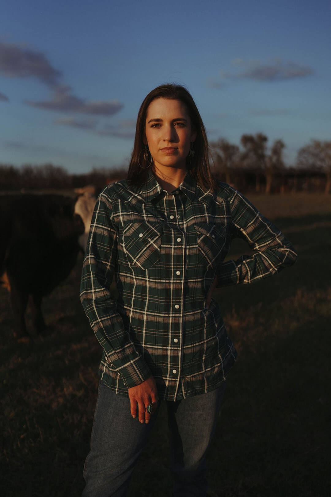 Woman wearing the Wrangler retro pearl snap western shirt.  The shirt is green plaid.  