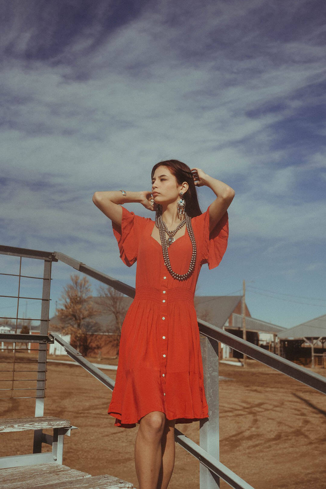 Woman standing on bleachers modeling the Wrangler Retro Red Dress.  The dress has ruffle short sleeves.  