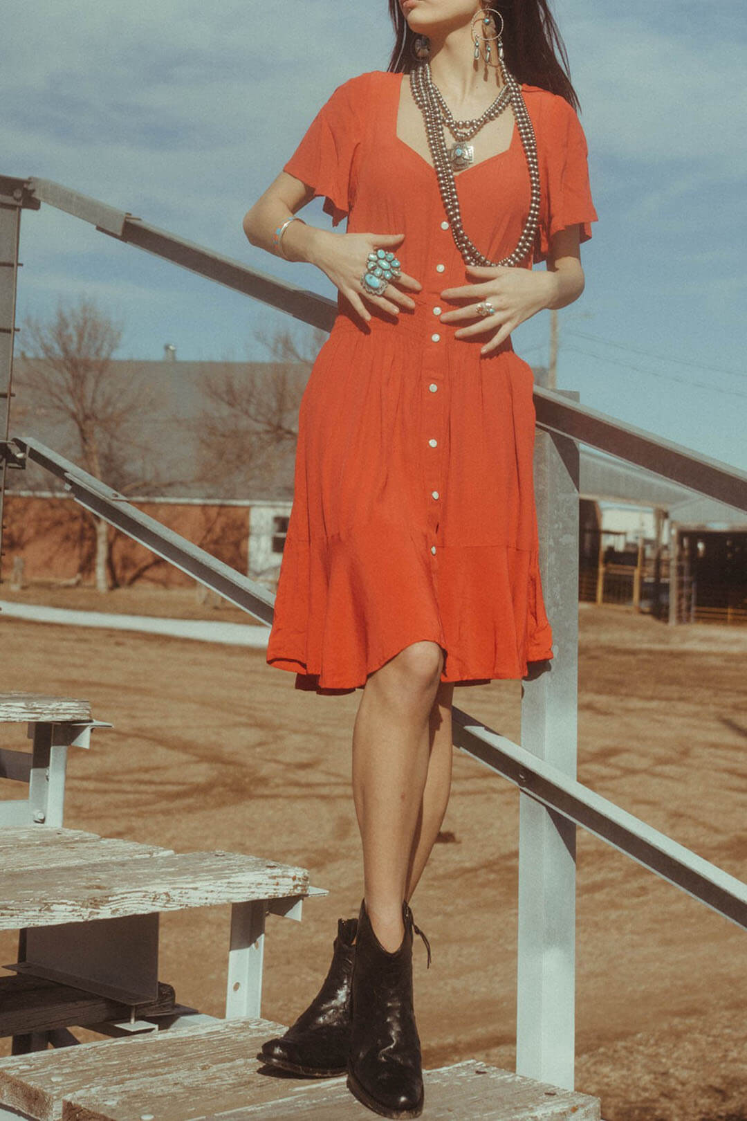 Woman modeling the Wrangler Retro Red Dress.  The dress is V-Neck and features white button snaps down the middle. 