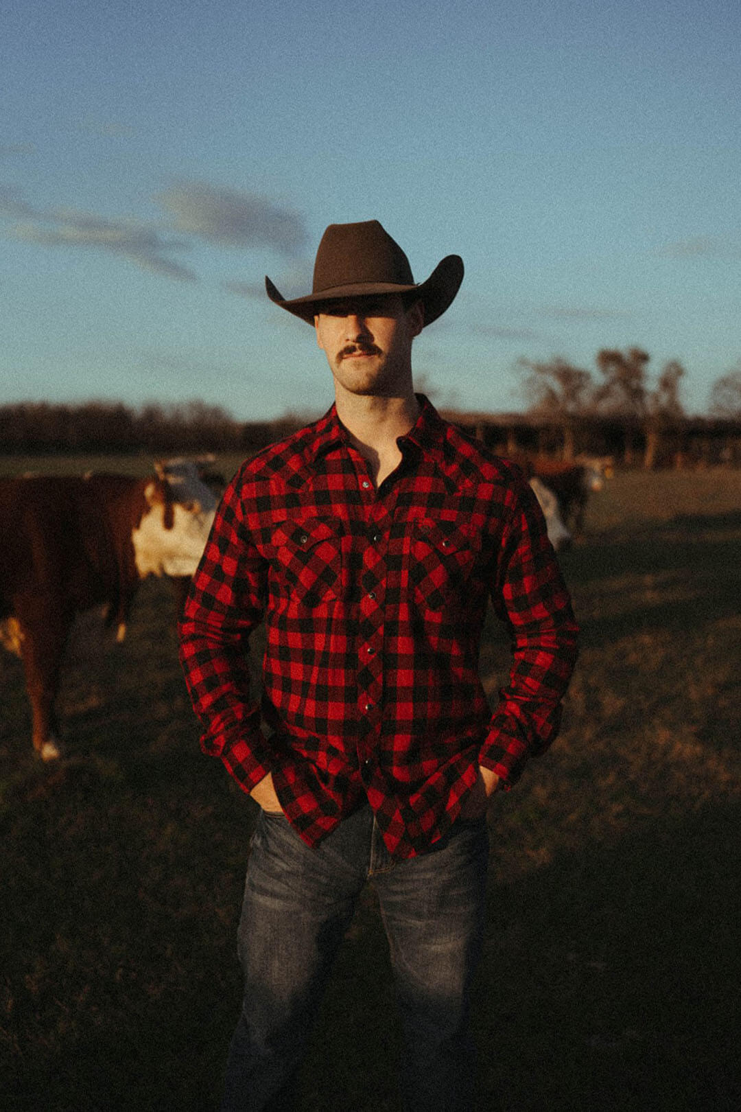 Man modeling the buffalo plaid long sleeve wrangler pearl snap shirt.  Can be worn tucked in or untucked . 