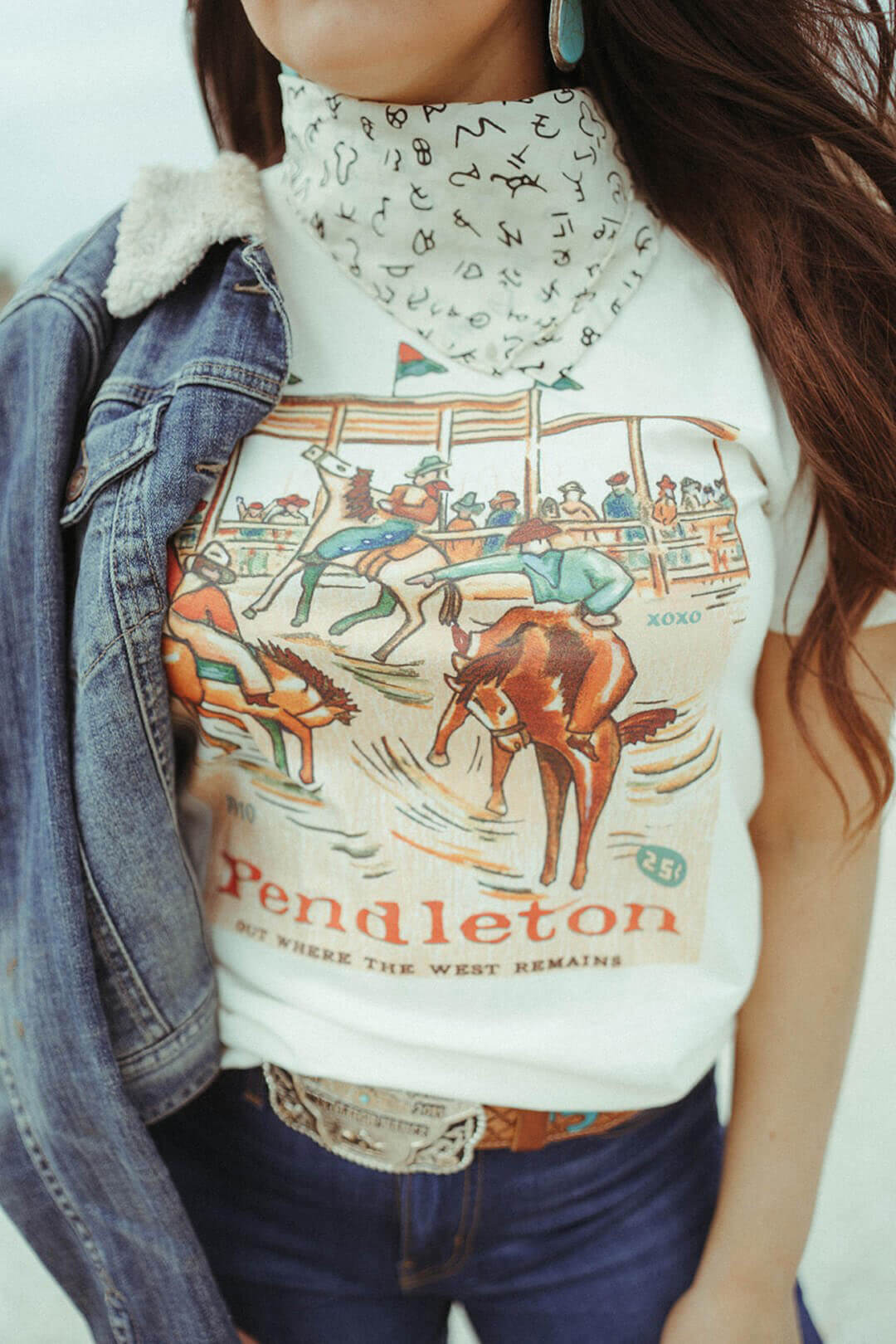 Close up image of the XOXO brand company tee "Out Where The West Remains" Pendleton  tee of image of rodeo with bucking broncs.