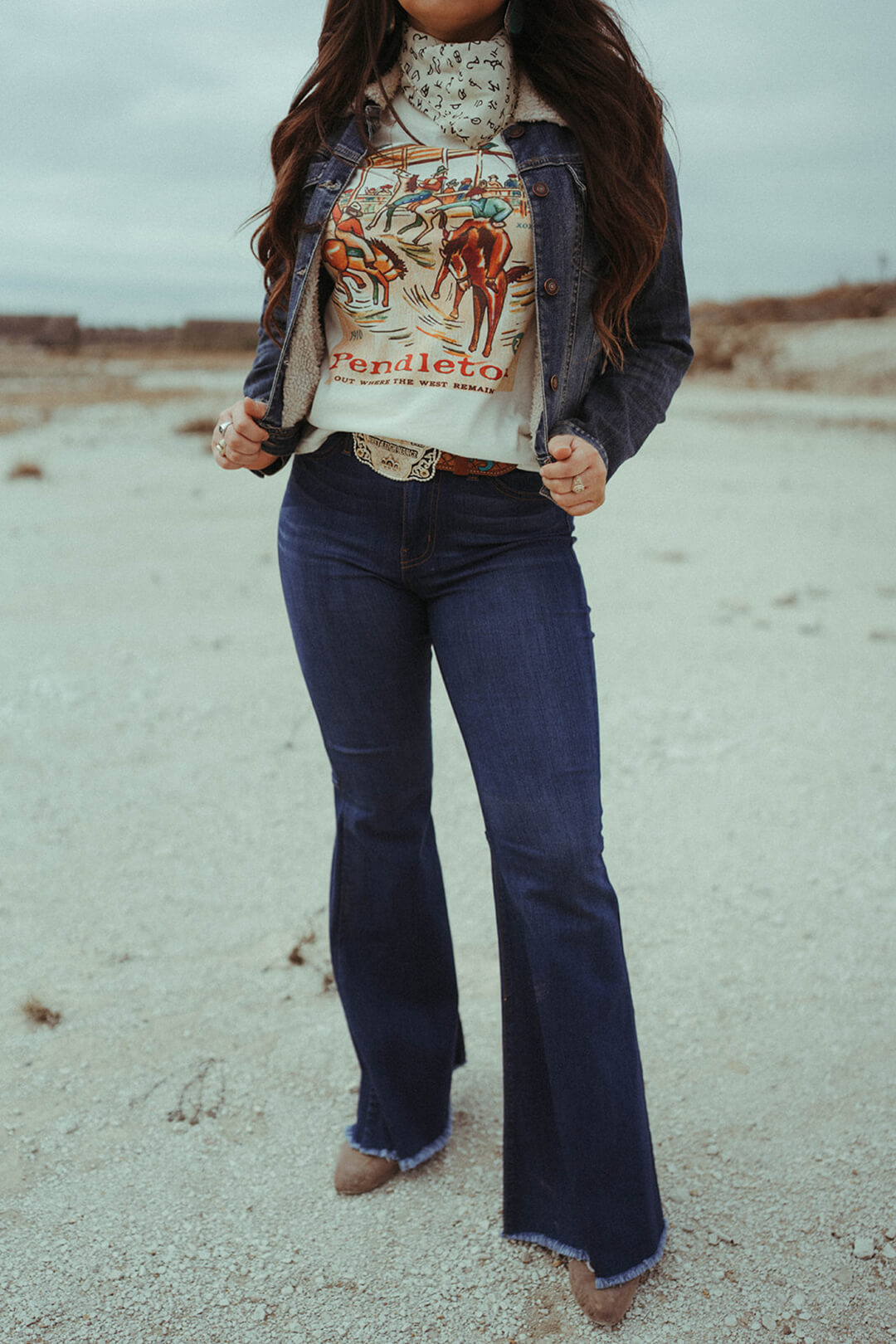 Woman modeling a pair of Judy Blue Flares.  The flares are zip fly and raw hem.  The pants are worn with the Pendleton graphic tee and the bandana scarf.