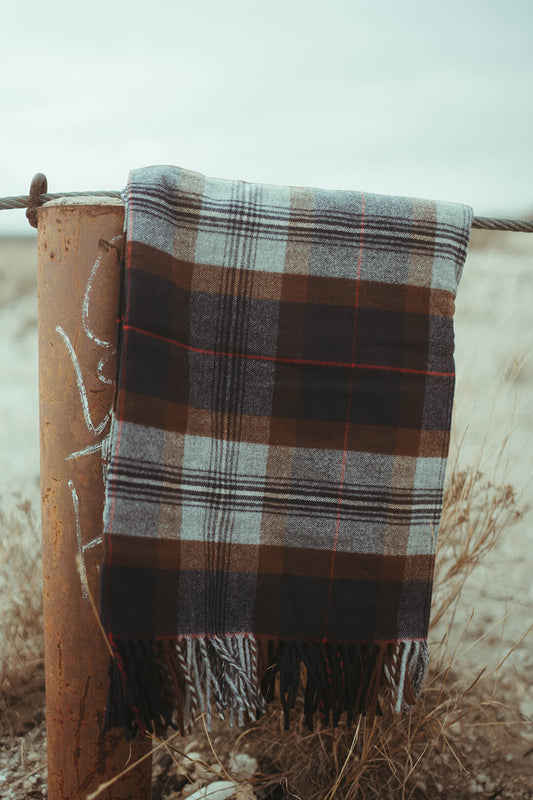 Picture of beautiful pendleton throw blanket with fringe on the ends.  The blanket is plaid colors blues, grays, and browns.  