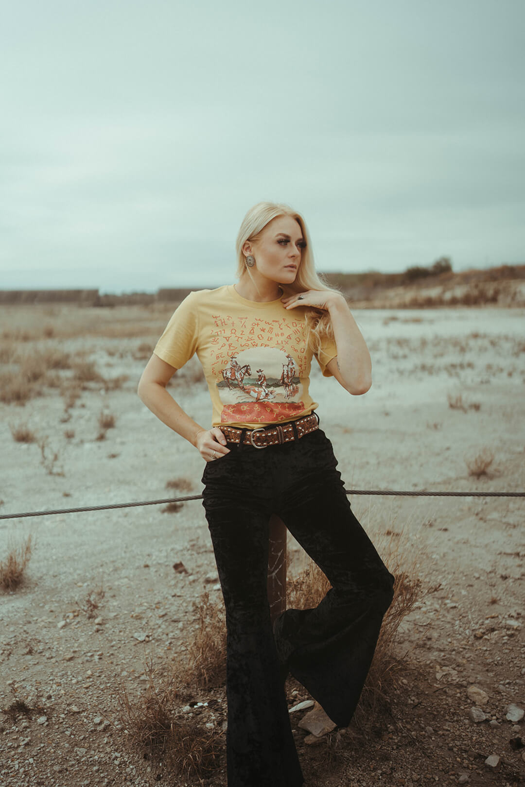 Picure of woman wearing a graphic tee yellow colored shirt with image of cowboys branding cows.  